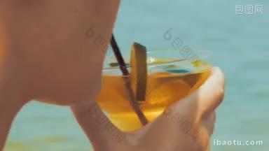 一个女人在海滩上用一杯鸡尾酒提神的特写镜头
